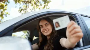 Persona al volante mostra una patente di guida attraverso il finestrino dell'auto