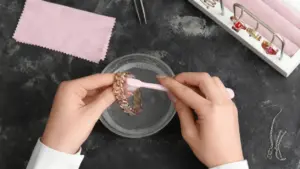 Mani che puliscono un bracciale con uno spazzolino su una ciotola di acqua insaponata